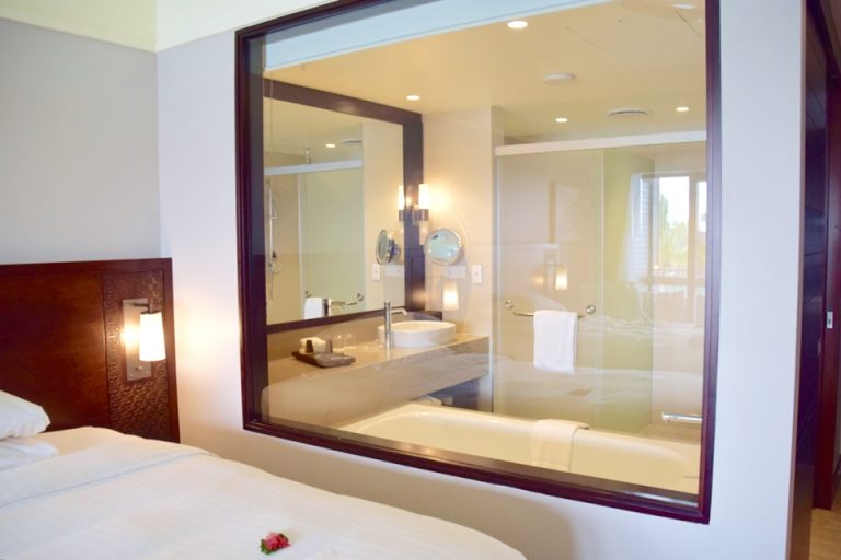 ベッドルームとバスルームは大きな窓で隔てられている