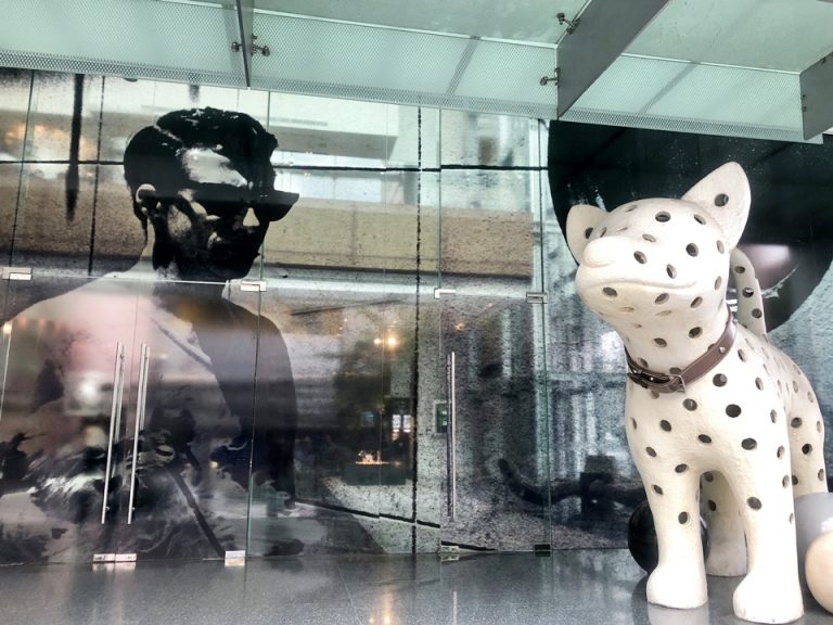 男性の写真と大きな犬のオブジェが目立つエントランス