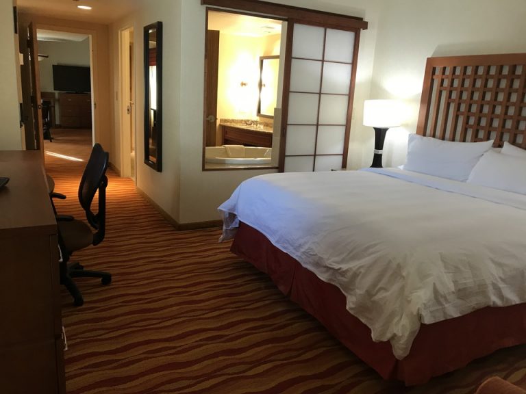 寝室その奥に右手にバスルーム左手に廊下奥にリビングスペースとラグジュアリースイートルーム