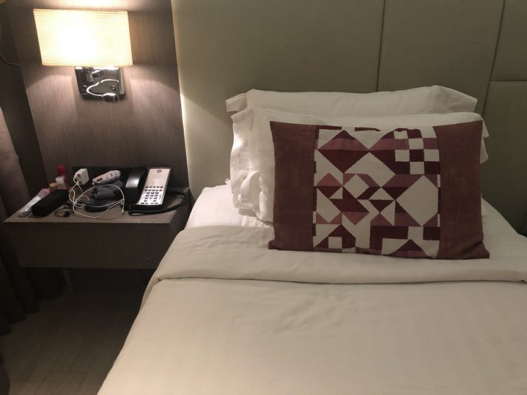 ベッドは硬めで、ベッドの横には1人1つ棚とコンセントが。