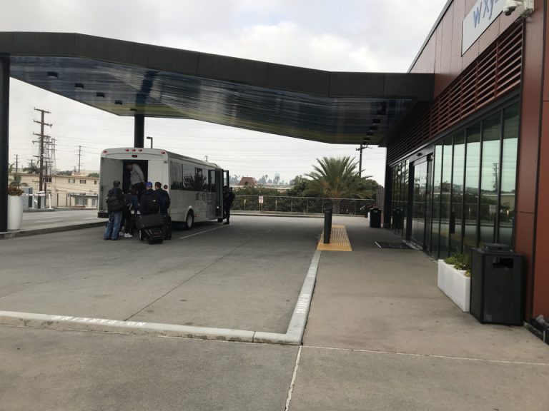 朝の空港までのホテルシャトルバスに乗る人達