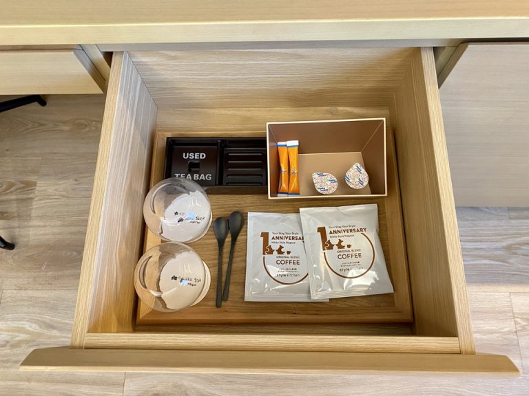 冷蔵庫の隣の棚にはコーヒーのドリップパック、砂糖とミルク、ガラスコップなどが入っています。