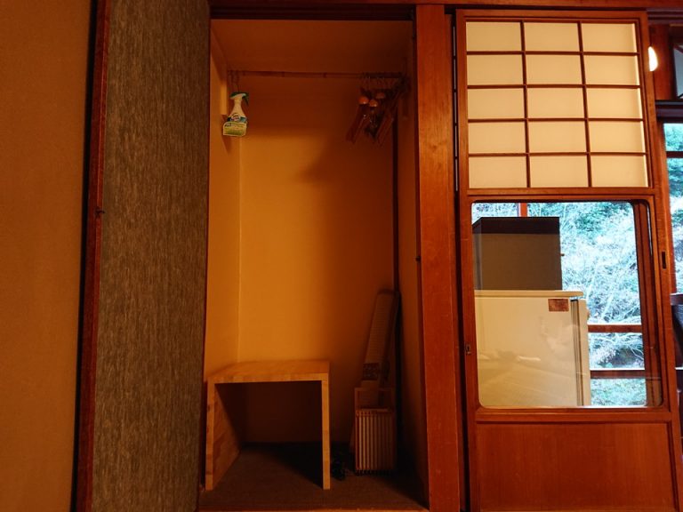 押入の中洋服かけと右に冷蔵庫と食器棚
