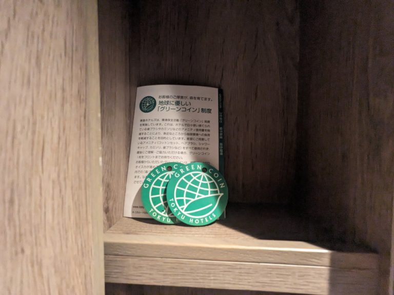鏡左側にホテルの環境保全対策,アメニティをすべて使わなかった場合はこのグリーンコインをフロントへ