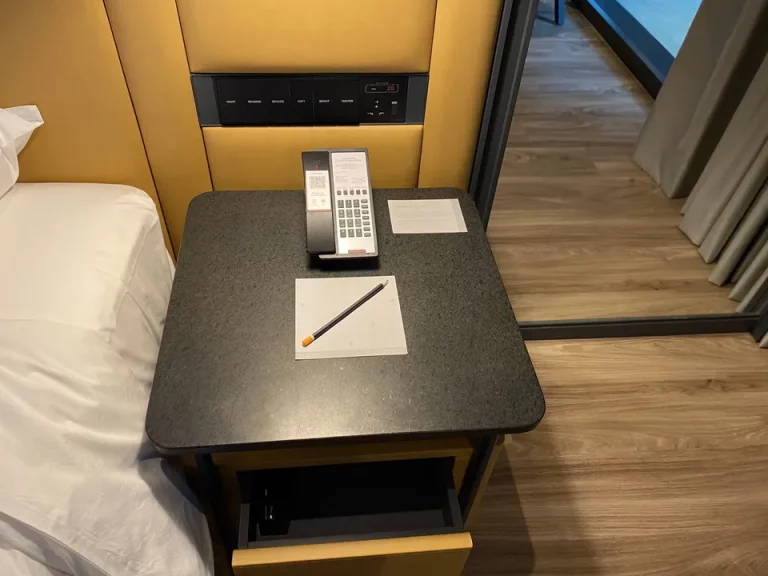 ベッドサイド。電話機とメモ帳、コンセント、照明調節。