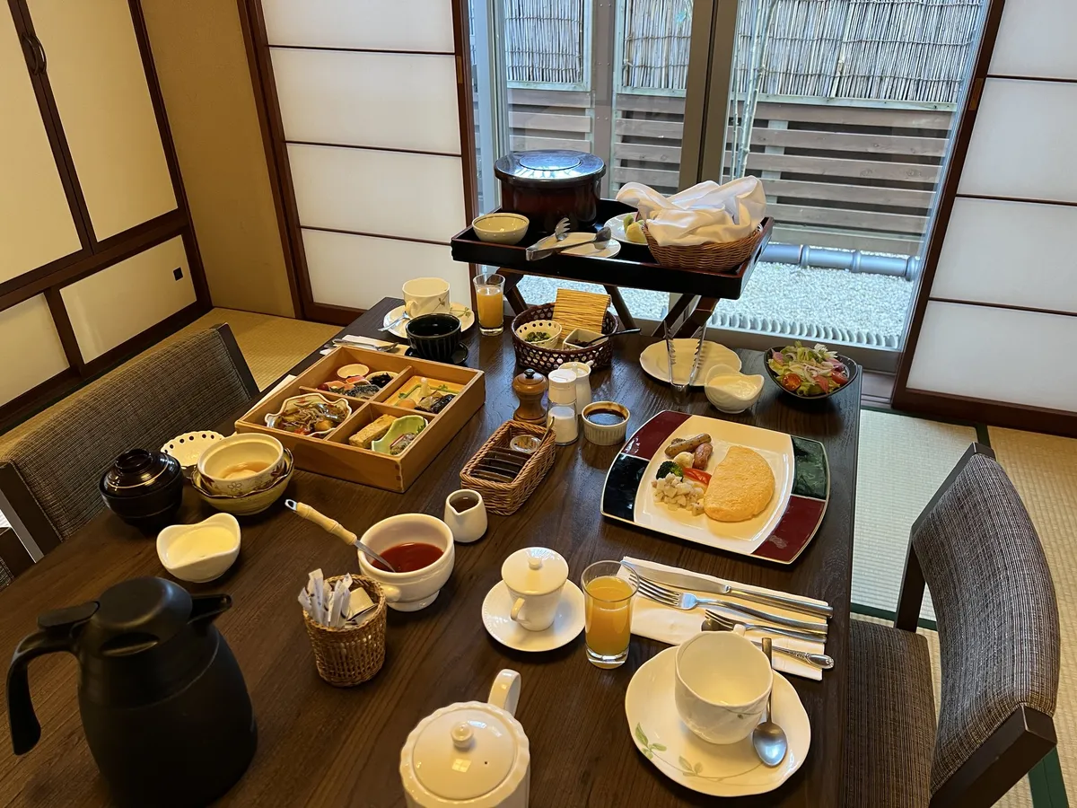 和室のテーブルに並べられた木箱入りの小鉢やオムレツ、サラダなどの朝食セット